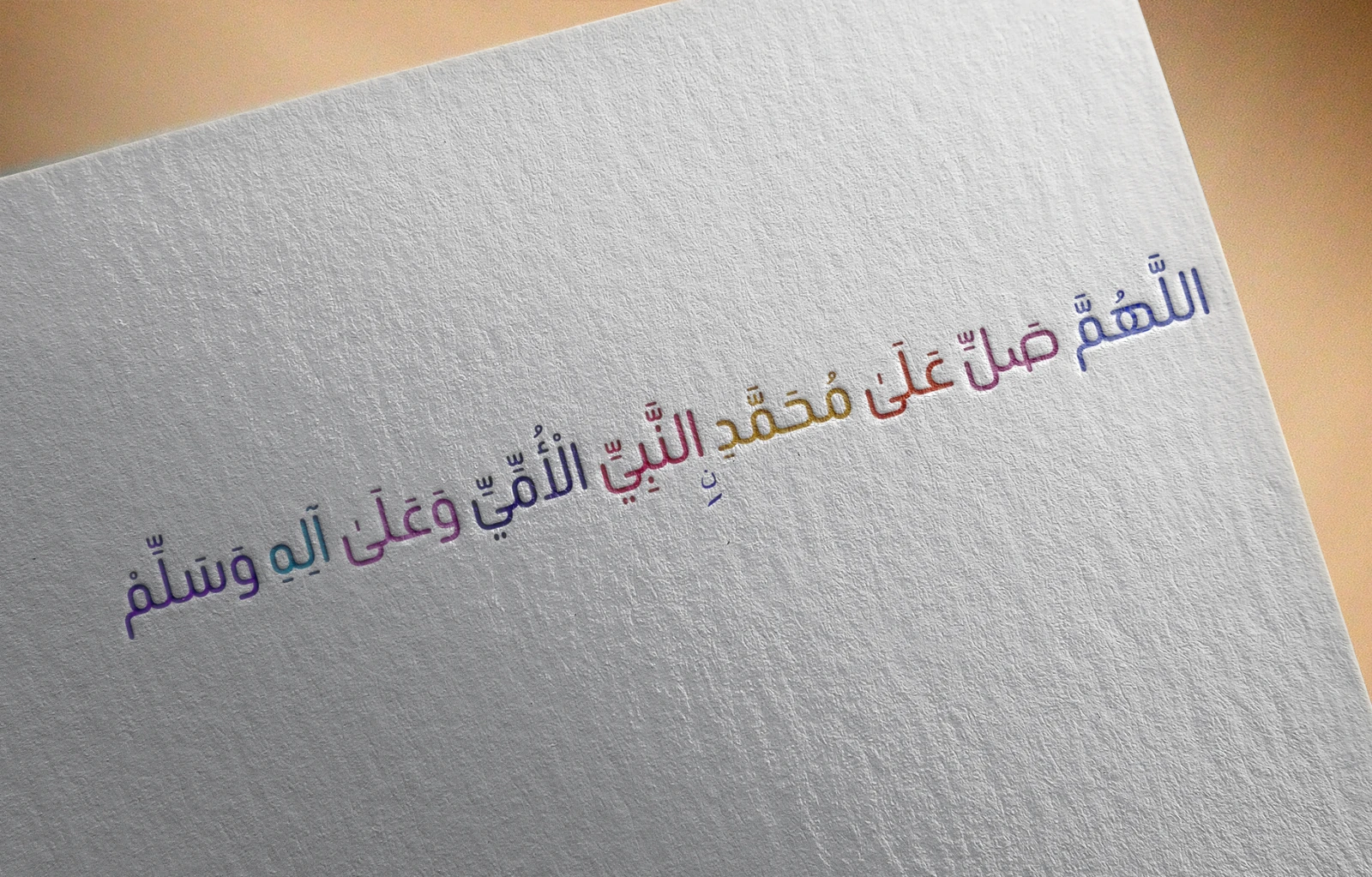 Finished photorealistic paper mockup with colorful Arabic salawat lettering pressed into textured white paper